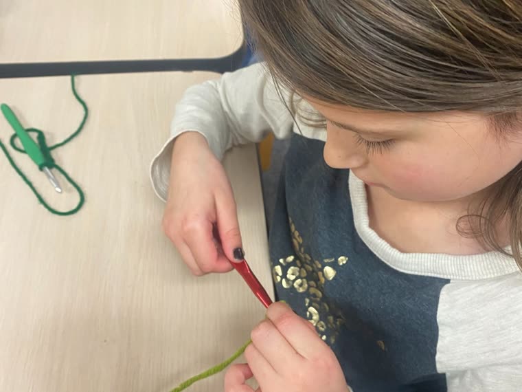 A student working slowly and carefully with yarn and scissors at her own pace