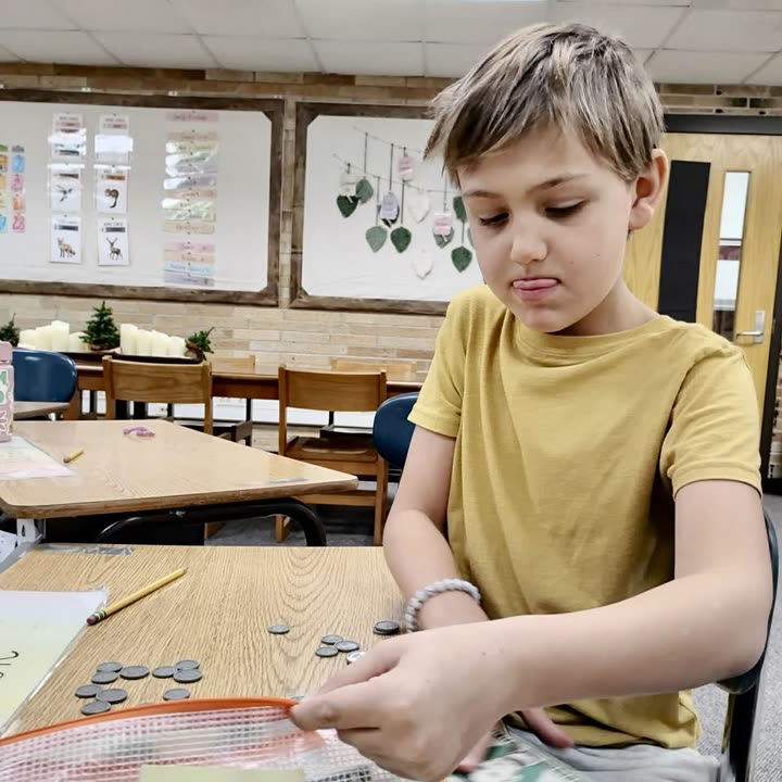 A student sorting and counting coins at a classroom table