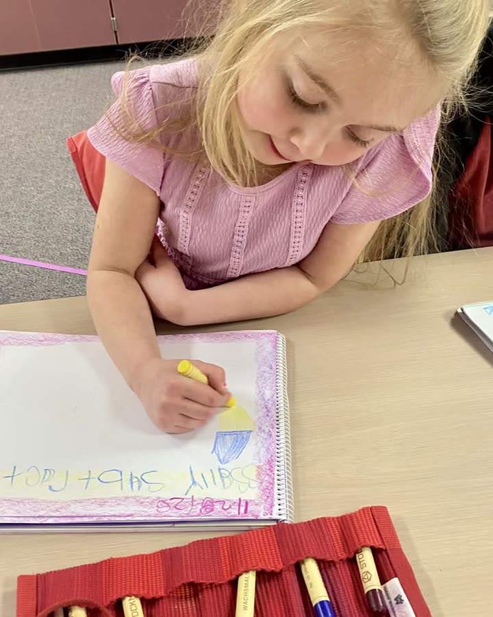 A student writing and illustrating a page in a hand-bordered main lesson book