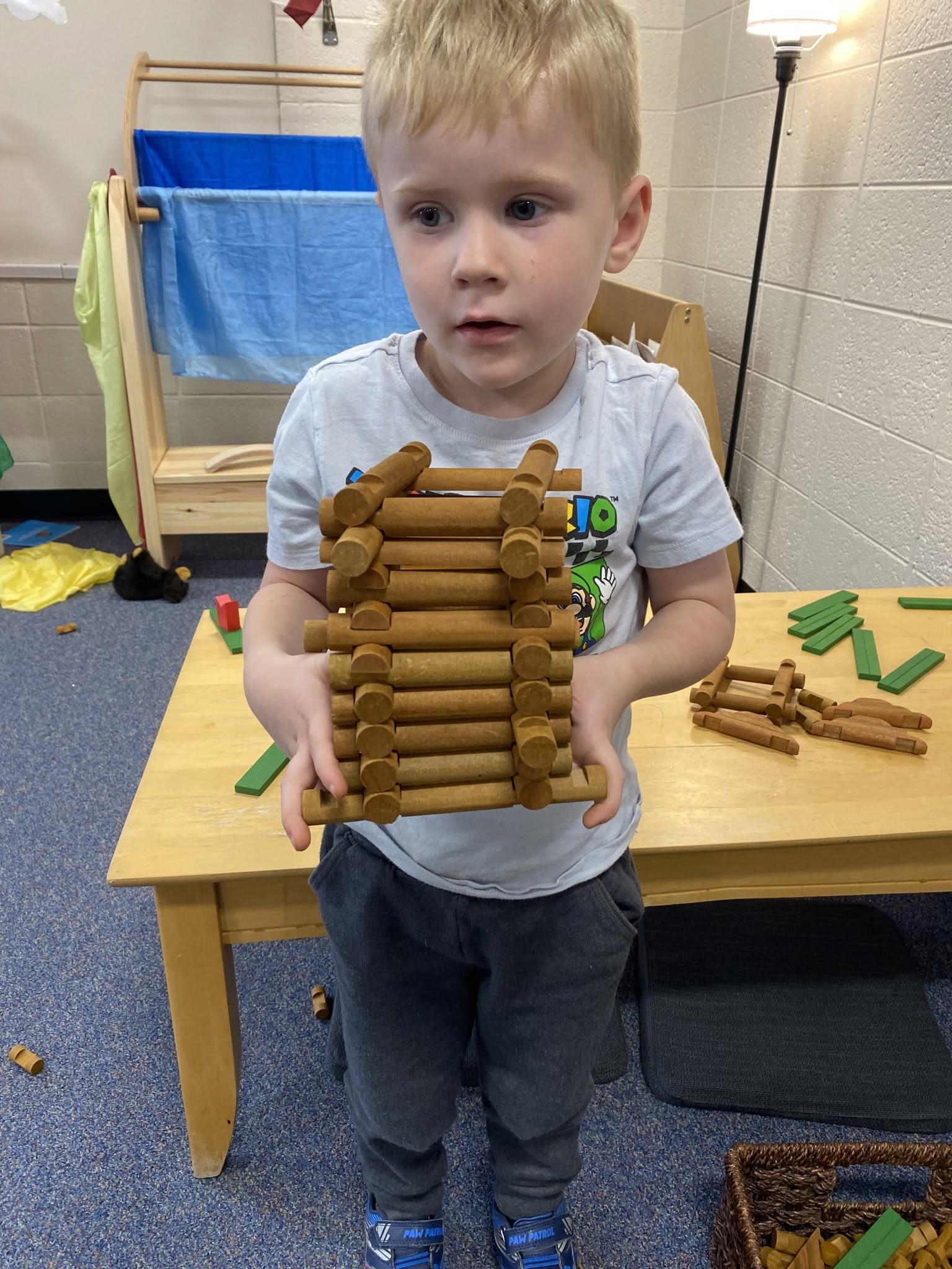 A student holding a wooden structure he built from interlocking pieces
